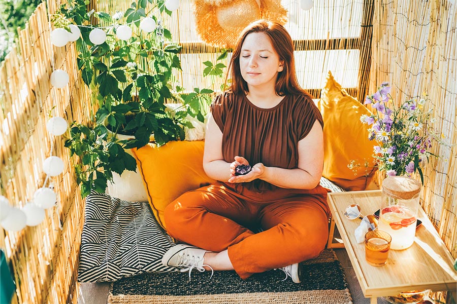 Mulher branca de cabelos ruivos sentada em posição de meditação